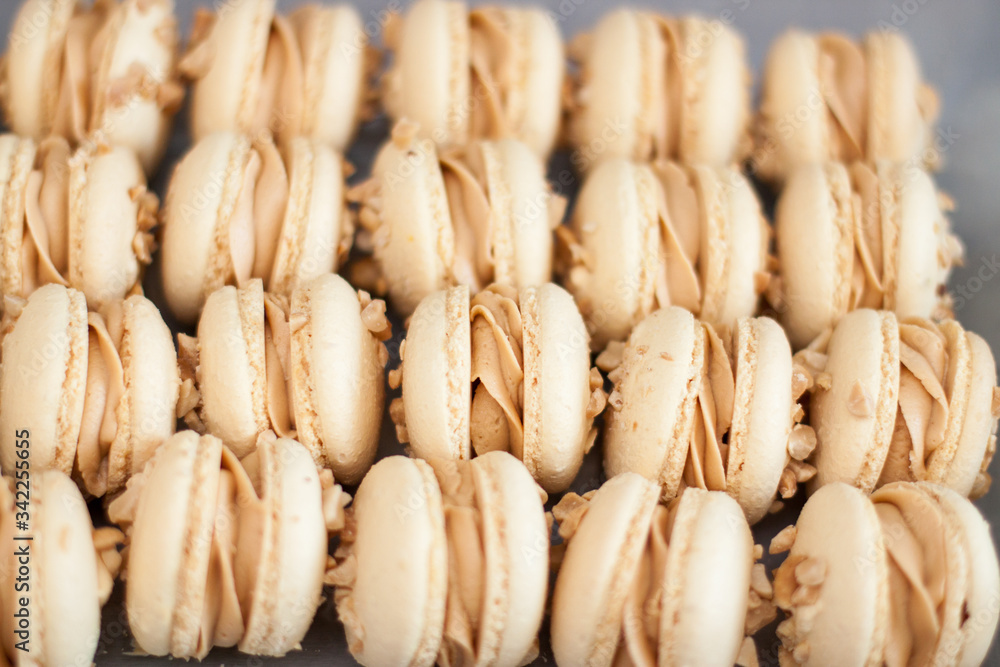 Homemade french macaroons with brown shells, peanut butter cream and peanuts. Selective focus. Homemade french macaroons with brown shells, peanut butter cream and peanuts. Selective focus.