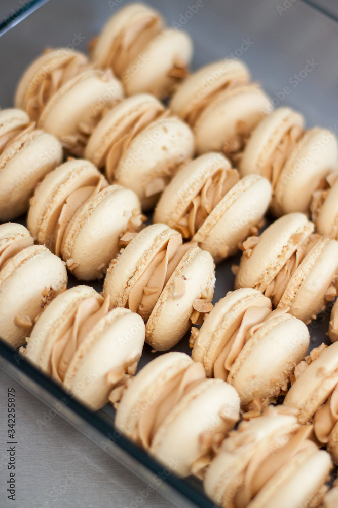 Homemade french macaroons with brown shells, peanut butter cream and peanuts. Selective focus. Homemade french macaroons with brown shells, peanut butter cream and peanuts. Selective focus.