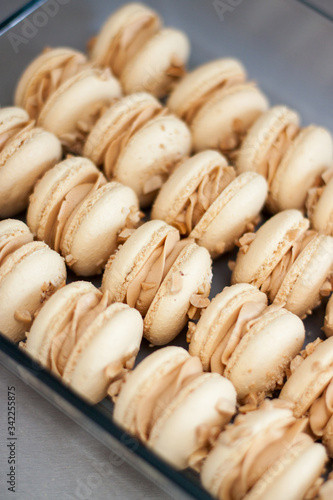 Homemade french macaroons with brown shells, peanut butter cream and peanuts. Selective focus.