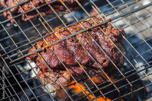 The piece of meat in spices lies on a lattice of a mobile barbecue and prepares.