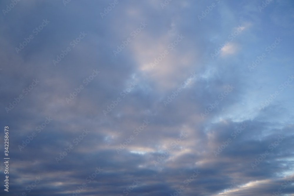 A beautiful evening blue sky at sunset with flaming bright light clouds. Warm evening. A beautiful evening blue sky at sunset with flaming bright light clouds. Warm evening.