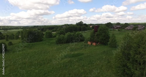 4K aerial summer morning high quality video footage of old unused rusty metal water pressure tower among lush green vegetation in Yaroslavl Oblast in central Russia