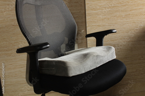Konstfotografi Grey Memory Foam Coccyx/sciatica back pain cushion in a black office chair