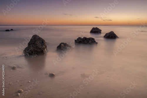 Long exposure shot of sunset rocks and calm seas