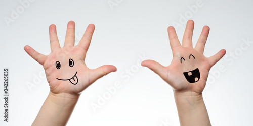 Children's hands with joyful faces painted on them