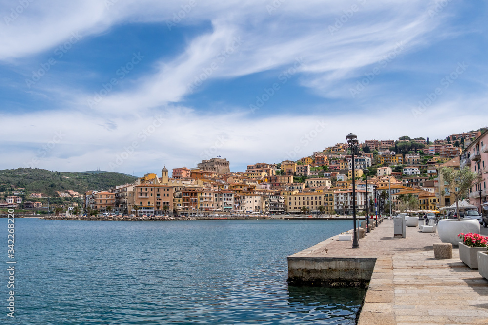 Dock on seafront in Porto Santo Stefano village in a sunny day with beautiful cloudy sky. Grosseto, Tuscany, Italy