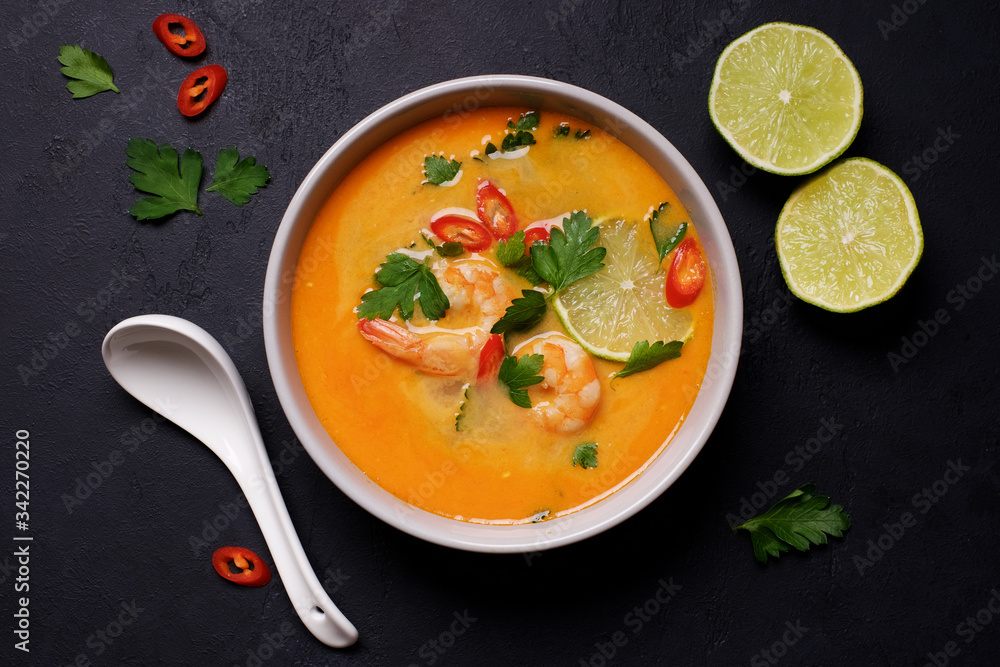 Tom Yam kung Spicy Thai soup with shrimp, coconut milk and chili pepper in bowl. Black stone background Tom Yam kung Spicy Thai soup with shrimp, coconut milk and chili pepper in bowl. Black stone background