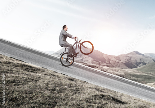 Businessman riding downhill by bike