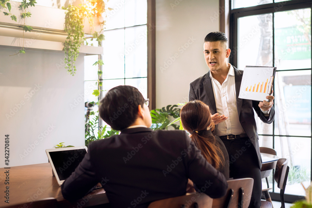 Co working space concept. Asian business looking in front of laptop while sitting at co-working space. The young manager is encouraging and appreciating his colleagues. Co working space concept. Asian business looking in front of laptop while sitting at co-working space. The young manager is encouraging and appreciating his colleagues.