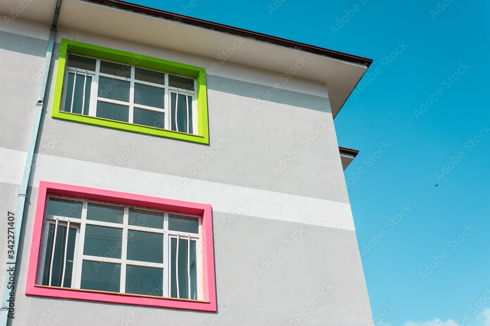 Grey building with colorful windows. Blue sky copy space. School building for educational concept.