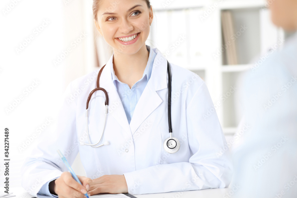 Friendly smiling doctor and patient sitting at the table. Very good news and high level medical service concept. Friendly smiling doctor and patient sitting at the table. Very good news and high level medical service concept.