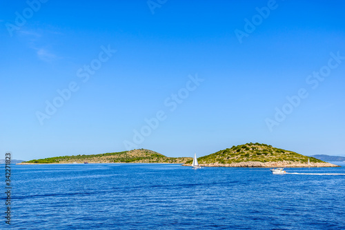 Adriatic coast with rocky beach, small islands, boats and sailing yachts in the blue sea, Croatia, Dalmatia