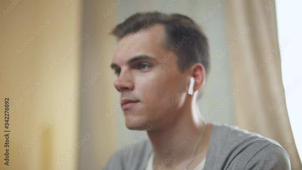 Young man makes a video conference and talking to the audience, working at a computer, online conference, quarantine, work from home. Young man makes a video conference and talking to the audience, working at a computer, online conference, quarantine, work from home.