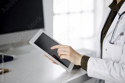 Unknown female doctor using tablet computer in clinic. Perfect medical service in hospital. Medicine concept