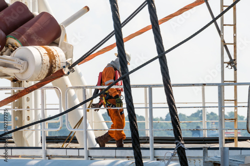 Riggers preparing sling on a derrick lay barge's stinger after its intallation during mobilization at port