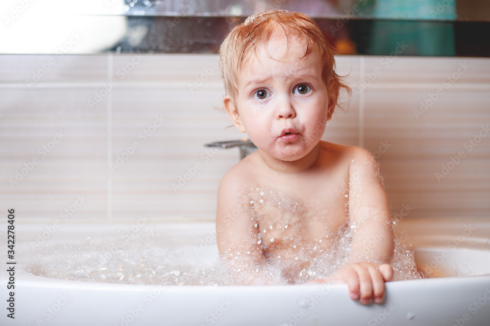 Happy laughing Infant baby toddler taking a bath playing with foam bubbles. Children care and hygiene concept. Happy laughing Infant baby toddler taking a bath playing with foam bubbles. Children care and hygiene concept.