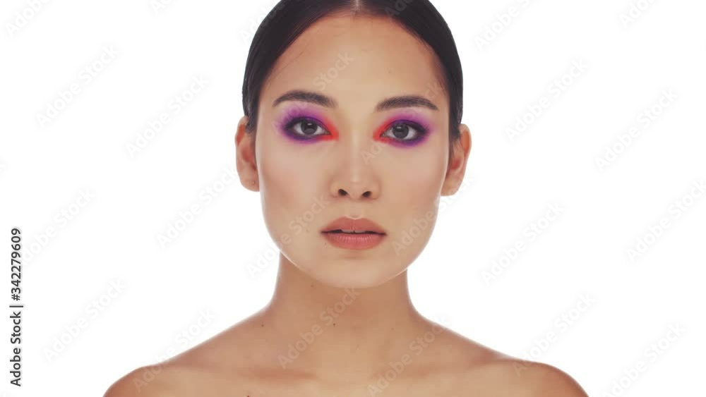 A beautiful half naked asian woman with bright fashion eye makeup is opening her eyes and looking to the camera isolated over white background in studio A beautiful half naked asian woman with bright fashion eye makeup is opening her eyes and looking to the camera isolated over white background in studio