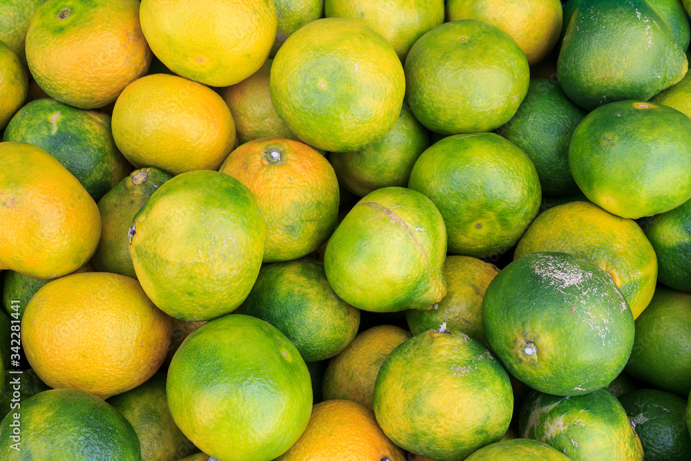 Green and orange mandarin background. Top view of fresh tangerines in fruit market
