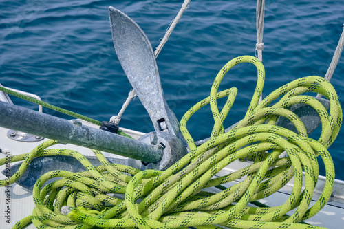 Close up Bow of the sail boat with anchor and light green rope. Sailing at summer sunny day. Yachting concept and sea background