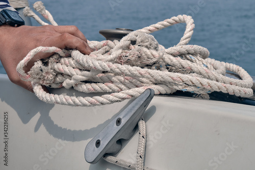 man hands pull the rope by a winch. Sailing at sunny summer day. Yachting concept and sea background © Evgeniy