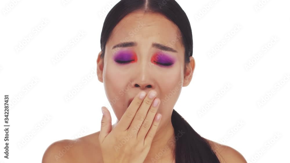 A beautiful young half-naked woman with bright fashion eye makeup is yawning isolated over white background A beautiful young half-naked woman with bright fashion eye makeup is yawning isolated over white background