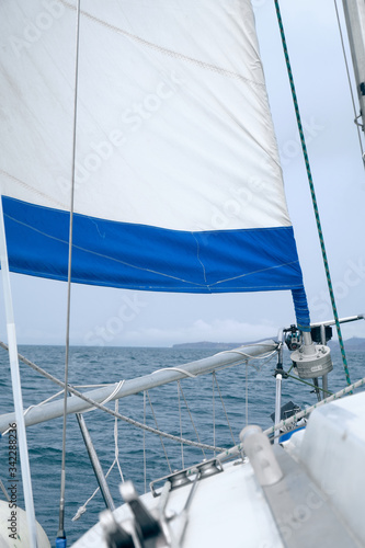 Cruising yacht bow with hoisted sails. Sailing at summer foggy day. Yachting concept and sea background © Evgeniy