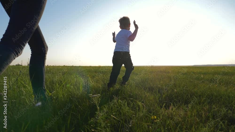 Young loving mom plays with her son outdoors. The child is happy and smiling. Happy family running around on the green grass, enjoying, having fun. The concept is a healthy lifestyle. Young loving mom plays with her son outdoors. The child is happy and smiling. Happy family running around on the green grass, enjoying, having fun. The concept is a healthy lifestyle.