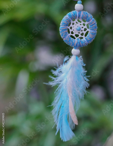 blue and white Dreamcatcher made of feathers leather beads and ropes  hanging in the garden  handmade