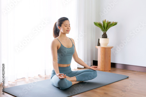 A young Asian woman practicing yoga indoors