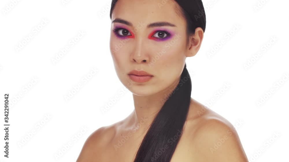 A charming young half-naked woman with bright fashion eye makeup is doing a silence gesture isolated over white background