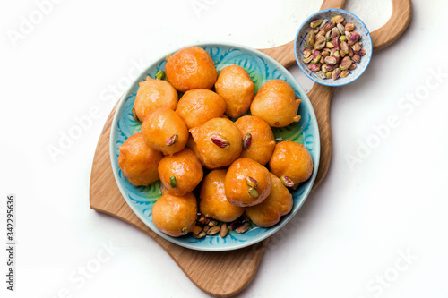 Lokma is a sweet dish in Greek, Turkish, Persian and Arabic cuisines. Dessert of sweet fried balls in a plate close-up on a white background