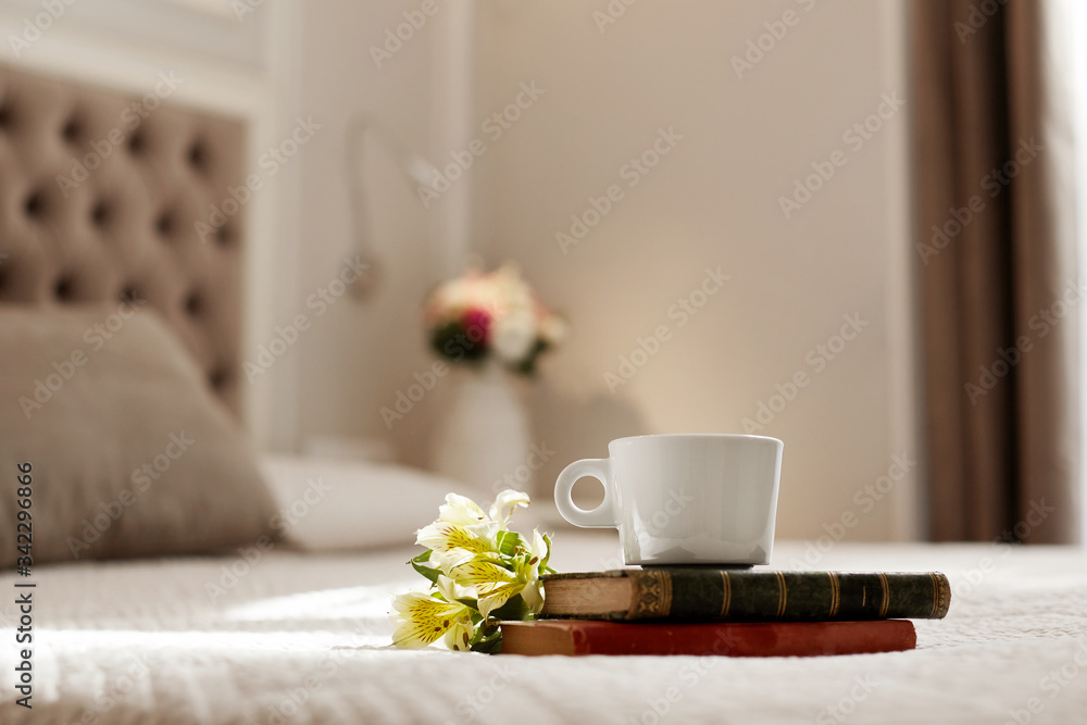 Books, flowers, and a coffee Cup lie on the bed. Romantic gift, romantic message, coffee in bed