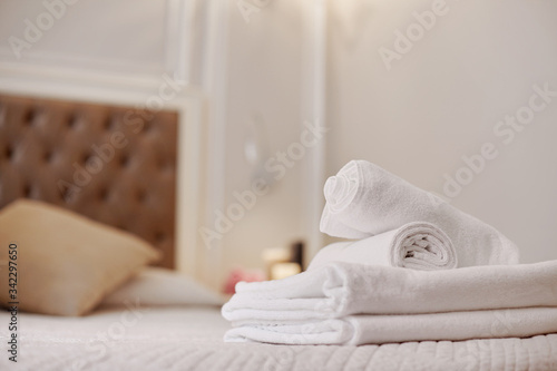 Neatly folded white towels lie on the bed in the room