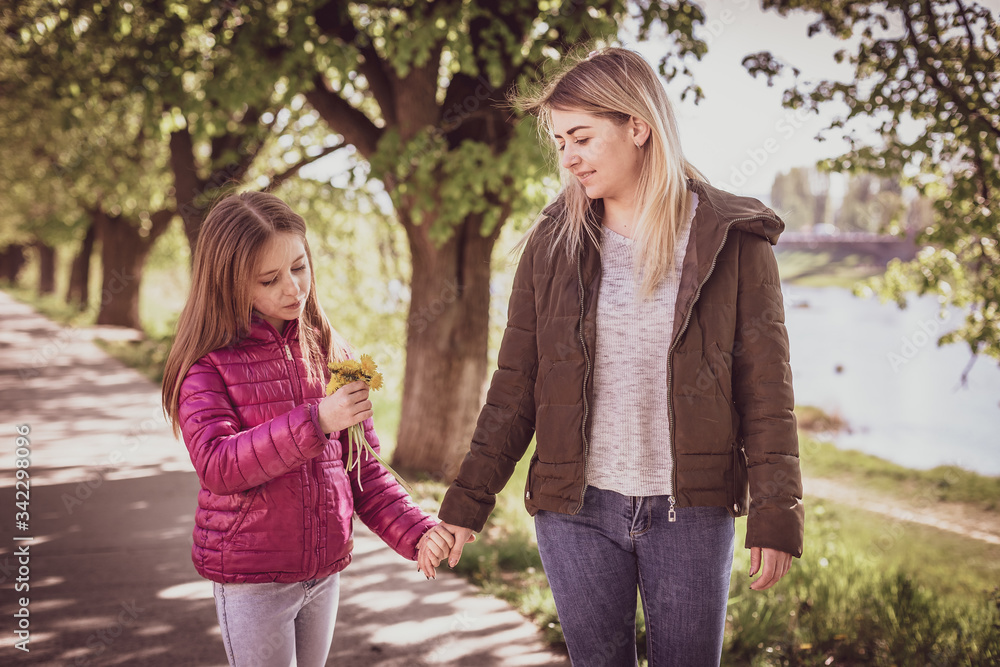 Young mother with baby walking in park near river. Spring morning. They look at each other Young mother with baby walking in park near river. Spring morning. They look at each other