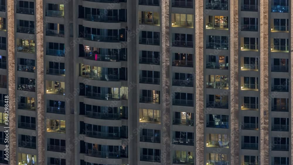 Night view of apartment building timelapse. High rise skyscraper with blinking windows with people moving inside. Aerial view from above. Pan left Night view of apartment building timelapse. High rise skyscraper with blinking windows with people moving inside. Aerial view from above. Pan left