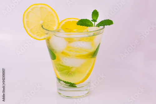  Lemon and mint lemonade with ice cubes in a stanan on a white background. A refreshing drink. Close-up.