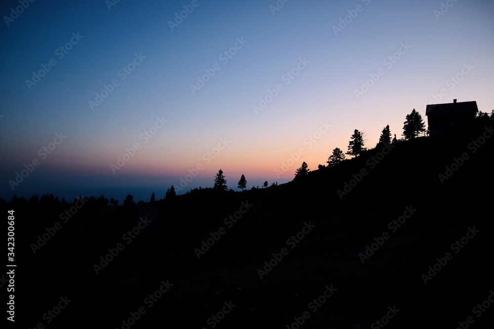 Mysterious silhouettes of building and trees in Velika Planina during dusk