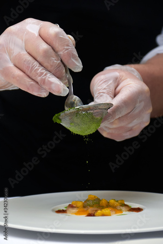 Close-up of cooking a dish in a round white plate by a waiter in a restaurant before dinner at a Banquet on Valentine's day. A professional chef prepares a dish