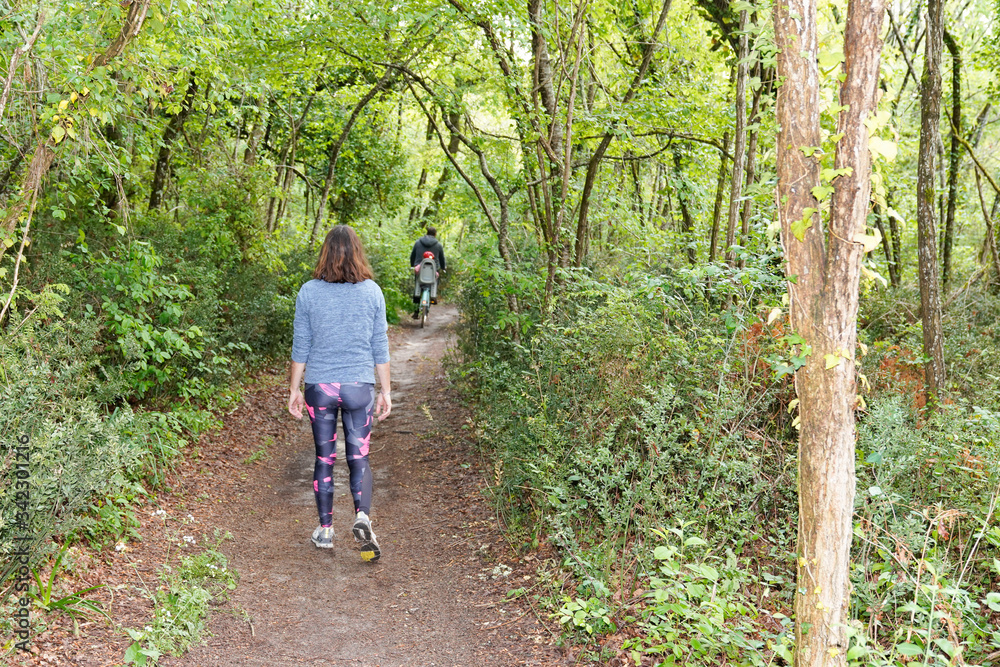 Woman sporty slim fit runner walking in forest outdoor trail in city park Woman sporty slim fit runner walking in forest outdoor trail in city park