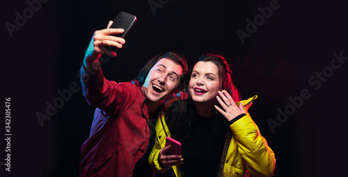 Young girl and boy (blogger) posing with smart phone, making selfie and video content. Broadcasts live with subscribers and followers. Advertisement concept. Copy space for text