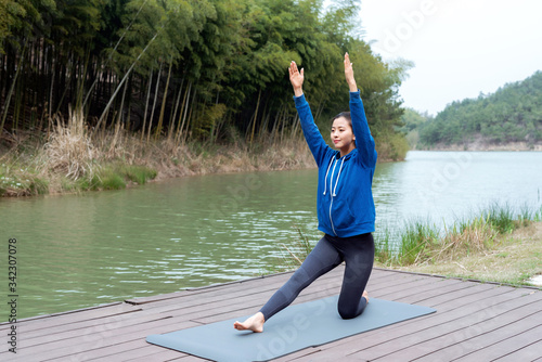 A young Asian woman practicing yoga in the outdoors