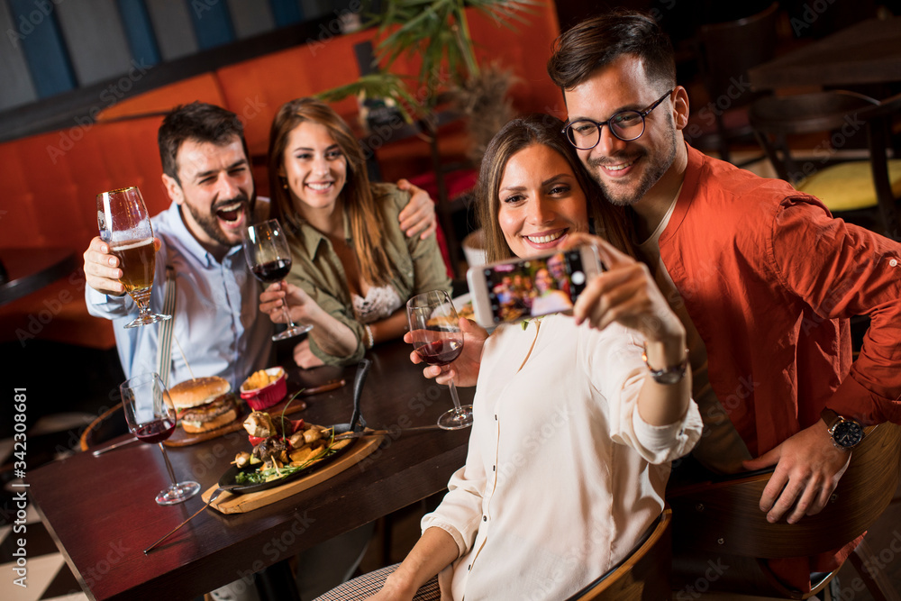 Obraz premium Handsome young friends making selfie and smiling while having a dinner in restaurant