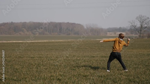 young sports man runs in the field and launches a boomerang into the sky