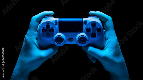 Hyman hands holding white video game gamepad in neon lights isolated on a black photo