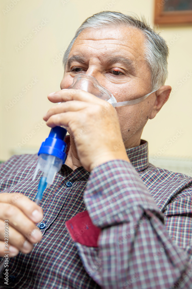Senior man using medical equipment for inhalation with respiratory mask, nebulizer Senior man using medical equipment for inhalation with respiratory mask, nebulizer