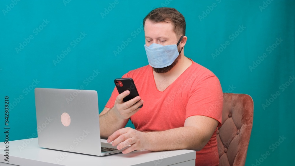 Man working from home. Using a smartphone. Bearded man in a protective mask works at home. Man working from home. Using a smartphone. Bearded man in a protective mask works at home.