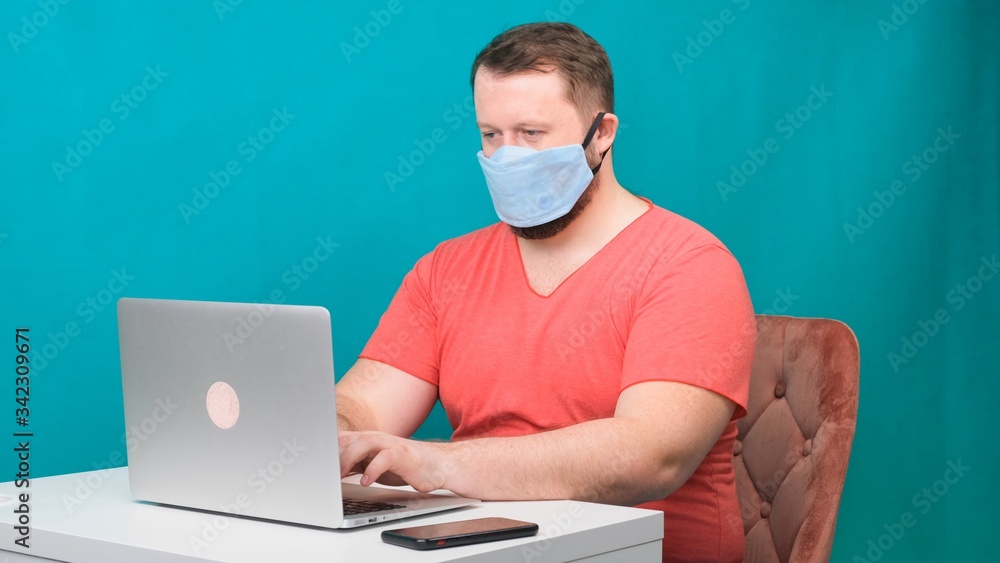 Side view portrait of a cheerful brunette man with surgical medical mask working on email laptop typing or chatting in social. Side view portrait of a cheerful brunette man with surgical medical mask working on email laptop typing or chatting in social.