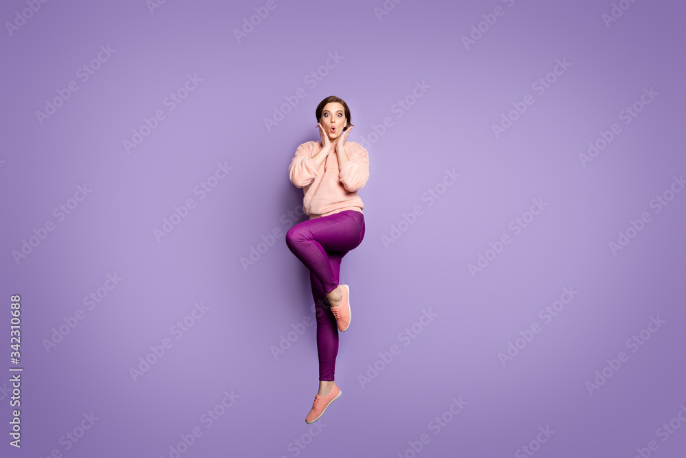 Full body photo of pretty funky lady jumping up high excited mood going crazy look unbelievable low shopping prices wear casual fluffy stylish pullover pants isolated purple color background