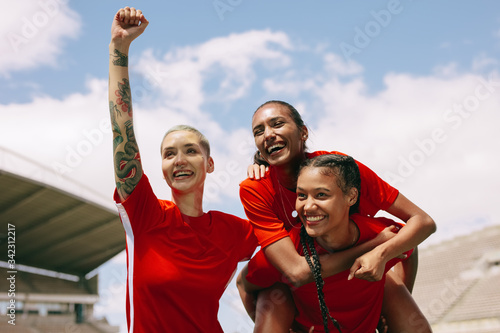 Teammates celebrating victory holding the goal scorer photo