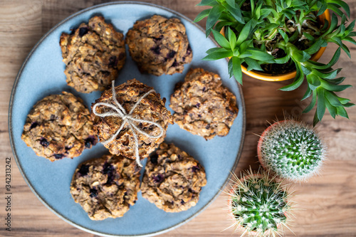 Set of easy to prepare and healthy  homemade oatmeal and blueberry cookies - on beautiful blue plate. Cookies are tied and decorated with string. Pots with cacti and succulents next to it.